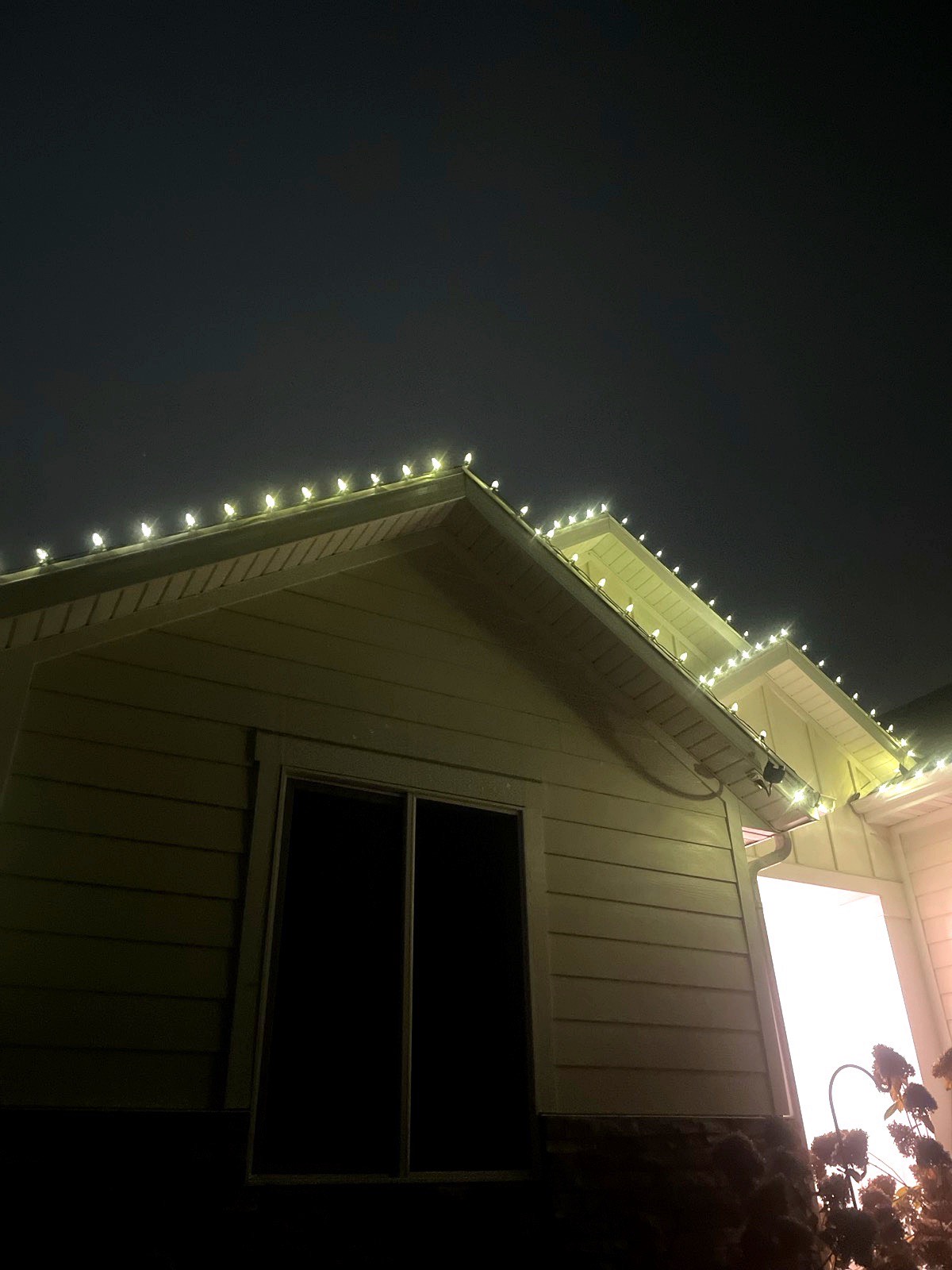 Home gables and eaves outlined in warm white lights